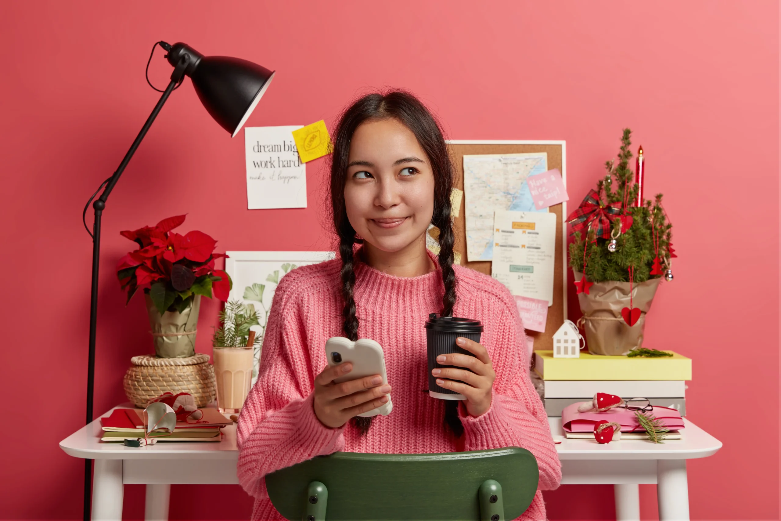 Seorang remote worker memegang smartphone dan kopi sambil bekerja di meja kerja yang rapi, menggambarkan pentingnya membangun personal branding sebagai remote worker melalui kehadiran profesional di dunia digital.